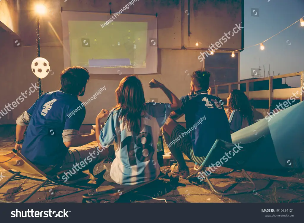 Menikmati anime dan sepak bola bersama teman Sekelompok teman menonton anime dan pertandingan sepak bola bersama